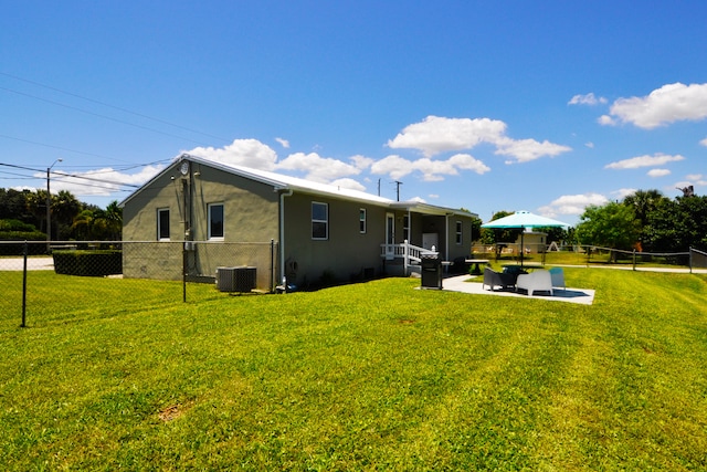 rear view of house featuring a patio area, central AC unit, and a yard