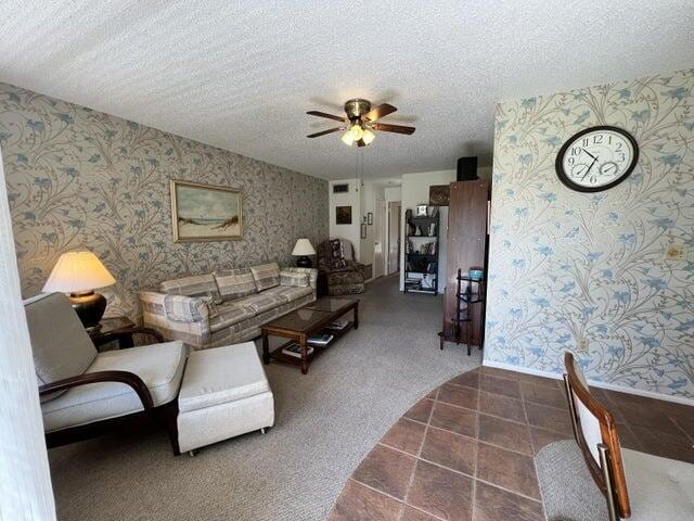 living room featuring carpet floors, a textured ceiling, and ceiling fan