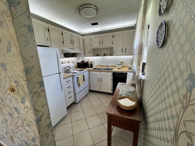 kitchen featuring white cabinetry, tasteful backsplash, white appliances, a textured ceiling, and sink