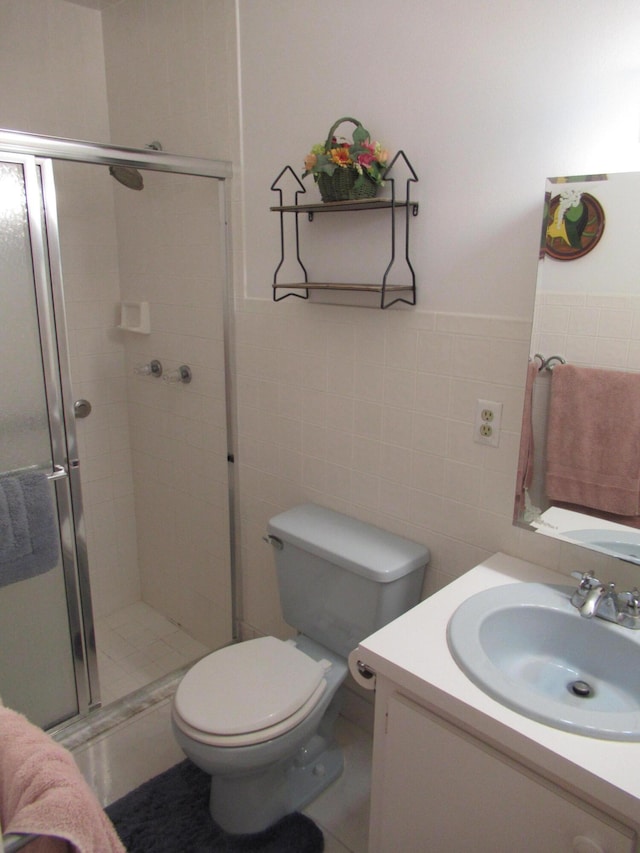 bathroom with tile walls, vanity, toilet, and walk in shower