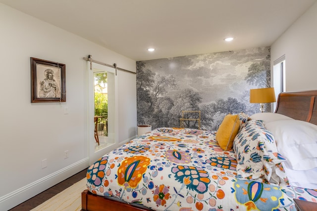 bedroom with a barn door, multiple windows, and hardwood / wood-style floors