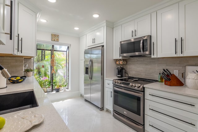 kitchen featuring stainless steel appliances, light stone counters, light tile patterned floors, decorative backsplash, and white cabinetry