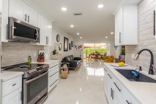 3593 Crab Apple Trl Unit C, Lake Worth, FL 33467 - kitchen featuring appliances with stainless steel finishes, a sink, backsplash, open floor plan, and crown molding