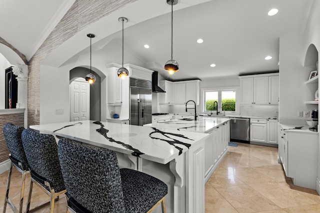 kitchen featuring a large island with sink, light stone countertops, wall chimney exhaust hood, vaulted ceiling, and stainless steel appliances