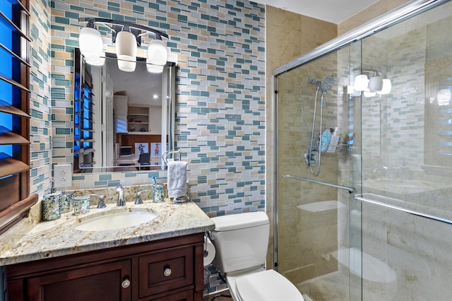 bathroom with a shower with door, vanity, and toilet