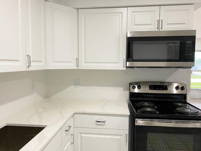 kitchen featuring white cabinetry, backsplash, light stone countertops, and appliances with stainless steel finishes