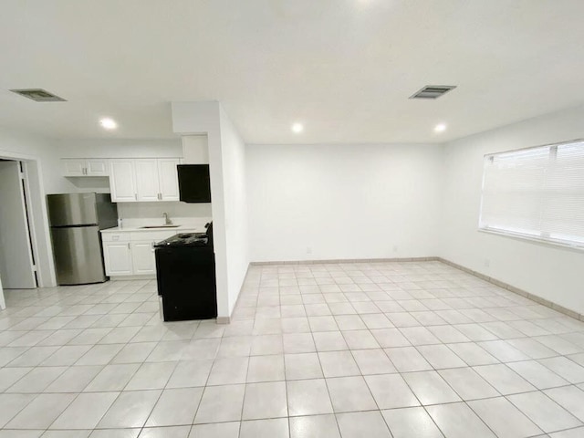 kitchen with range with electric stovetop, stainless steel fridge, light tile patterned floors, and white cabinets