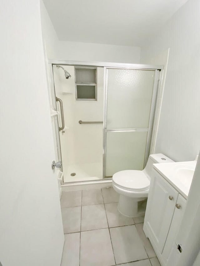 bathroom with a shower with shower door, tile patterned floors, toilet, and vanity