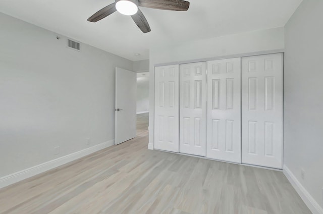 unfurnished bedroom with light wood-type flooring, ceiling fan, and a closet