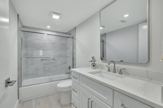 full bathroom featuring toilet, hardwood / wood-style floors, vanity, and shower / bath combination with glass door