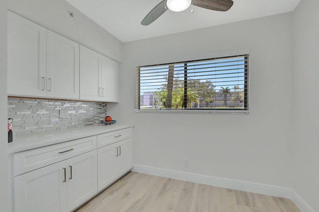 kitchen featuring light hardwood / wood-style floors, backsplash, white cabinetry, and ceiling fan