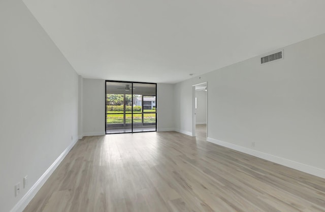 spare room with floor to ceiling windows and light hardwood / wood-style flooring