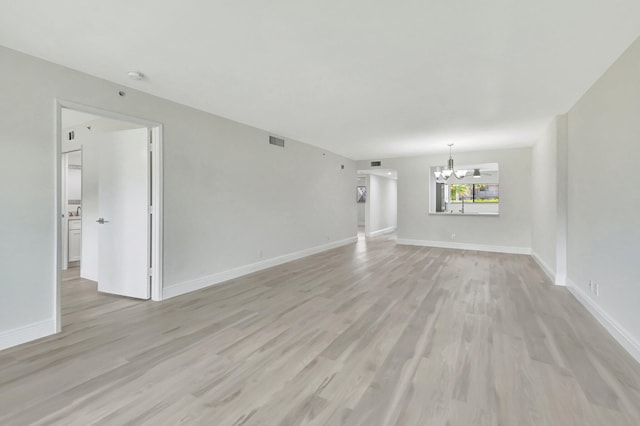 unfurnished living room featuring light hardwood / wood-style floors and a notable chandelier