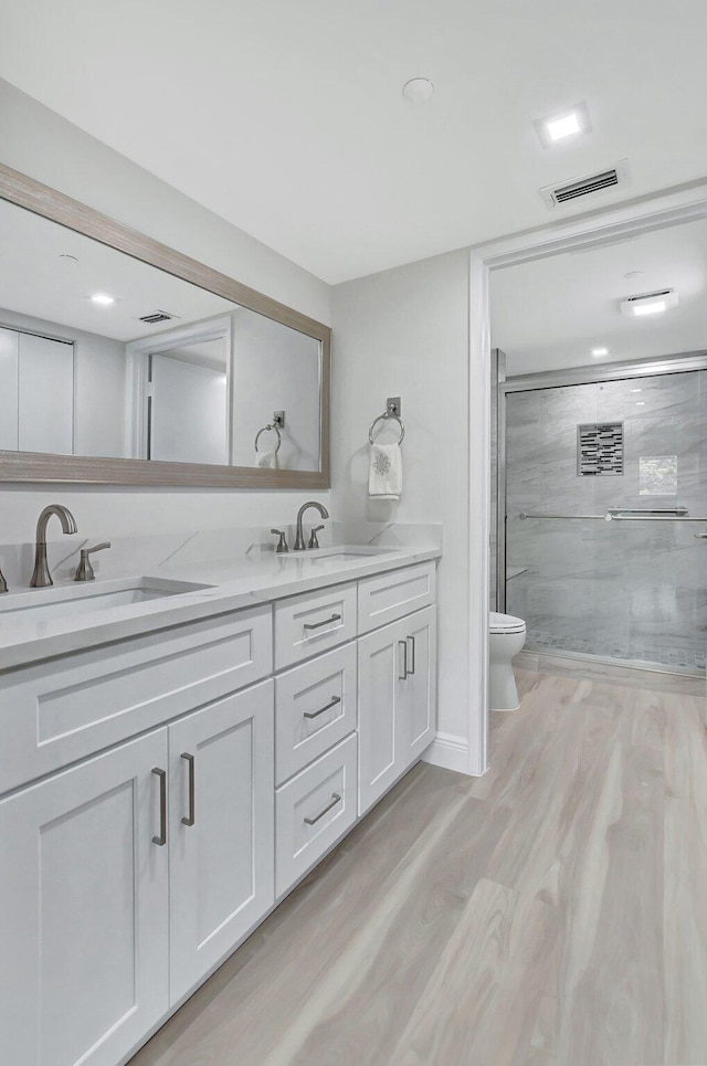 bathroom with vanity, toilet, wood-type flooring, and an enclosed shower