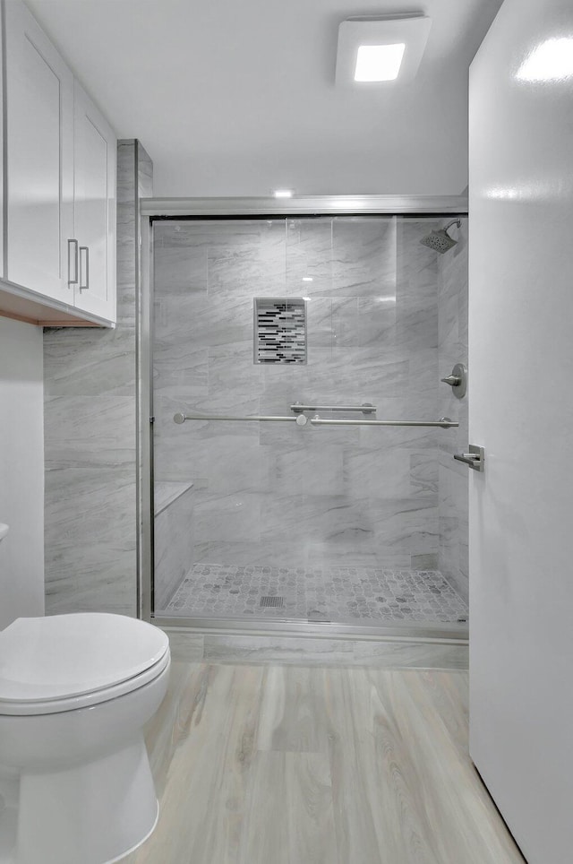 bathroom featuring toilet and a shower with shower door