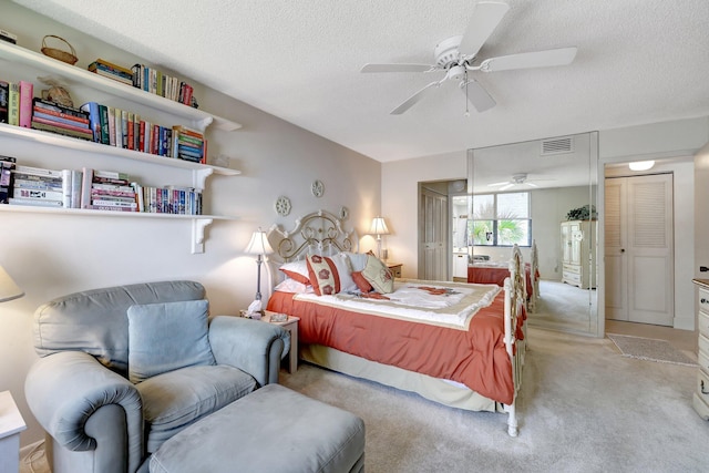 bedroom with a textured ceiling, ceiling fan, and light colored carpet