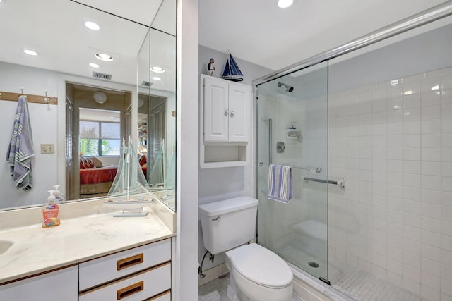 bathroom featuring a shower with door, toilet, and vanity