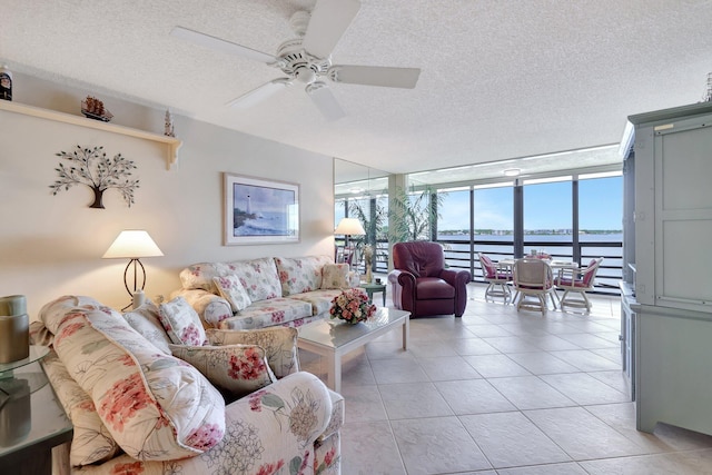 tiled living room with expansive windows, a water view, a textured ceiling, and ceiling fan