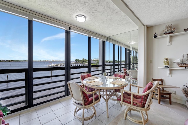 dining area featuring a water view, a textured ceiling, light tile patterned floors, and floor to ceiling windows