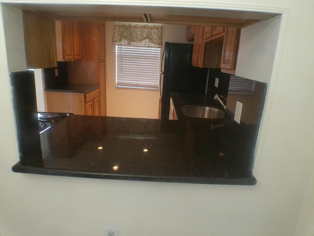 kitchen featuring sink, black fridge, and dark stone counters