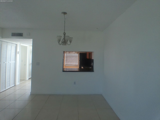 unfurnished room with a chandelier and light tile patterned floors