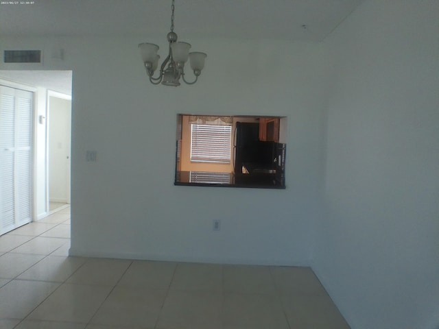 tiled empty room featuring a notable chandelier