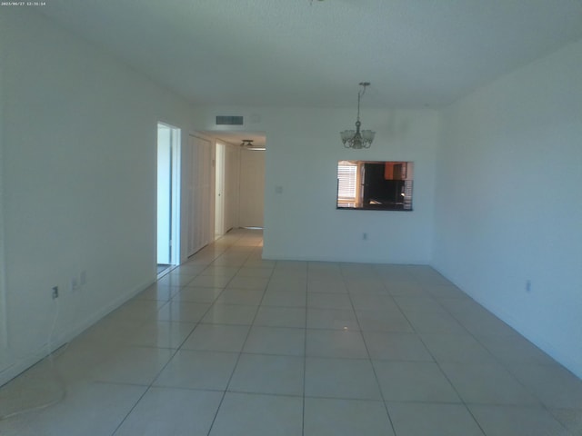 empty room with a chandelier and light tile patterned floors