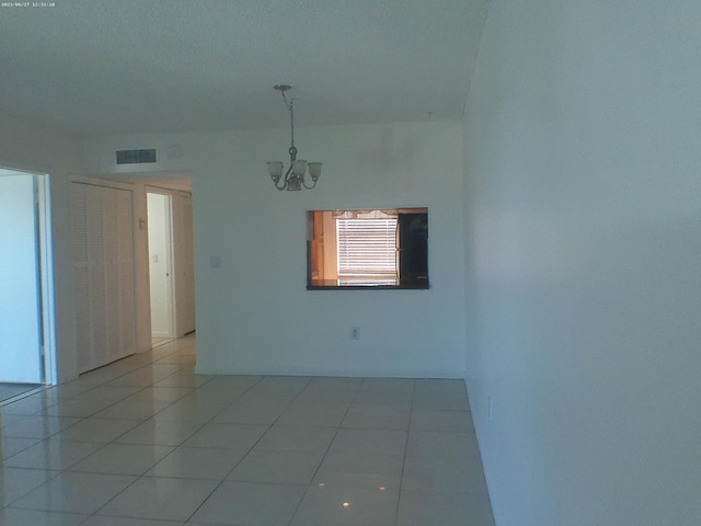 tiled empty room with a chandelier