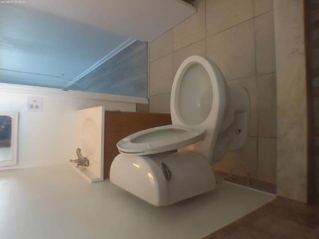 bathroom featuring toilet, tile patterned flooring, and tile walls