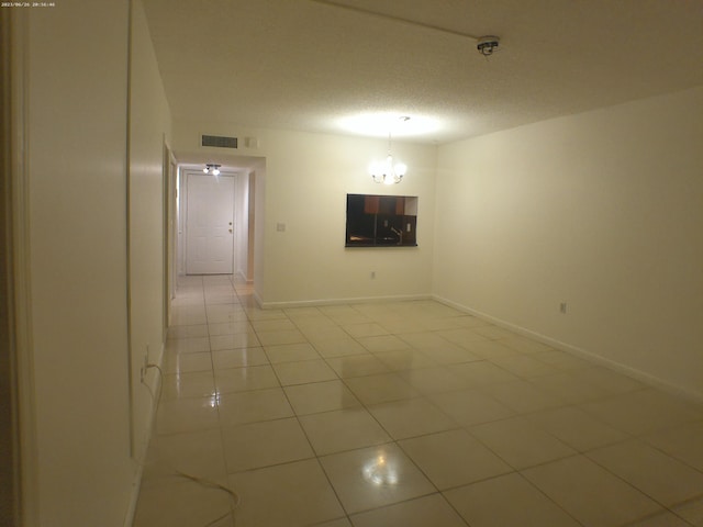 unfurnished room with a notable chandelier, tile patterned flooring, and a textured ceiling