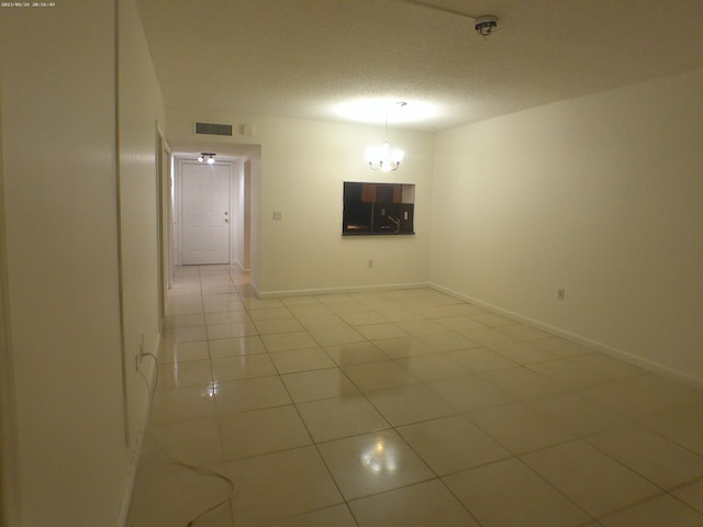 tiled empty room featuring a textured ceiling