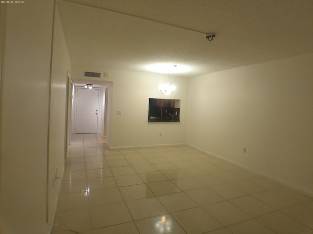 tiled empty room featuring a textured ceiling