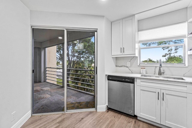 kitchen with white cabinetry, dishwashing machine, light hardwood / wood-style floors, light stone countertops, and sink