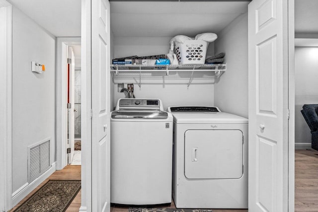 clothes washing area with independent washer and dryer and light hardwood / wood-style floors