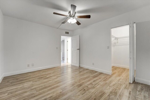 3601 Inverrary Dr Unit 102, Lauderhill, FL 33319 - unfurnished bedroom featuring light wood-style floors, baseboards, a walk in closet, and ceiling fan