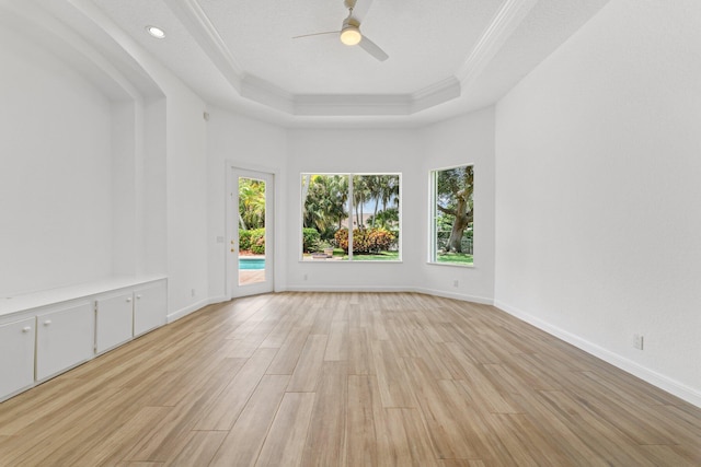 spare room with ceiling fan, crown molding, a tray ceiling, and light hardwood / wood-style floors