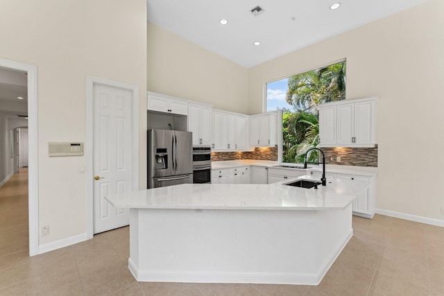 kitchen featuring backsplash, a center island, a high ceiling, white cabinetry, and stainless steel appliances