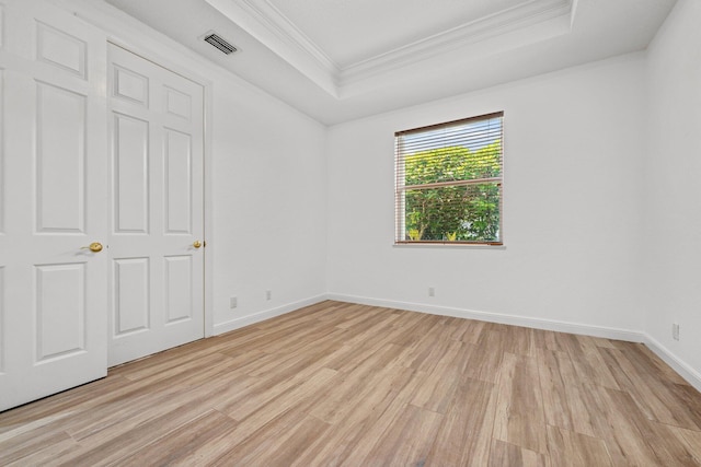 unfurnished room with crown molding, light wood-type flooring, and a tray ceiling