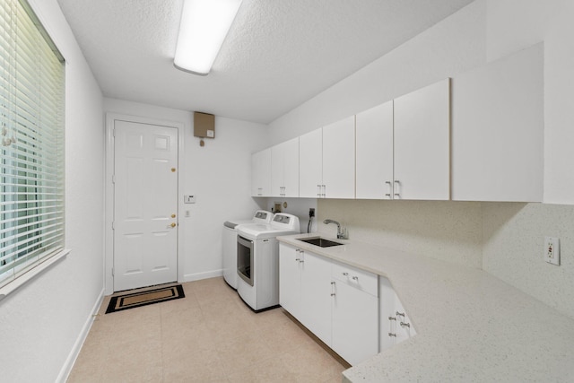 laundry area featuring washing machine and dryer, sink, a textured ceiling, and cabinets