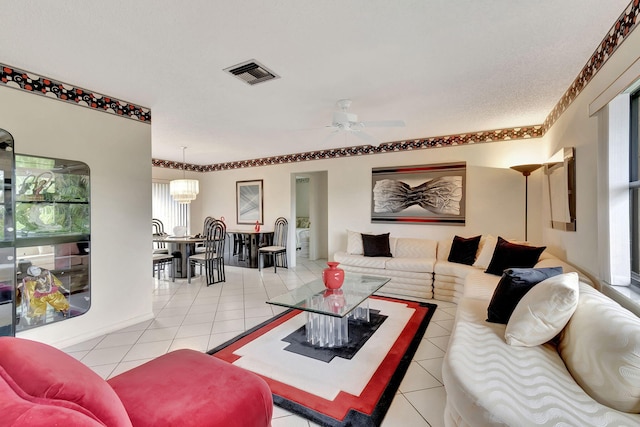 living room with light tile patterned flooring and ceiling fan with notable chandelier