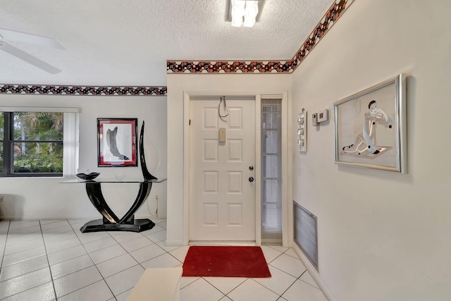 tiled foyer entrance with a textured ceiling and ceiling fan