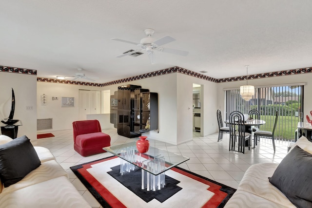 living room with a textured ceiling, ceiling fan with notable chandelier, and light tile patterned floors