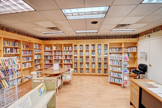 home office with light hardwood / wood-style floors and a paneled ceiling