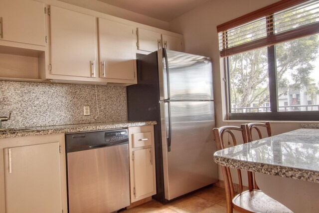 kitchen with light tile patterned flooring, decorative backsplash, and appliances with stainless steel finishes