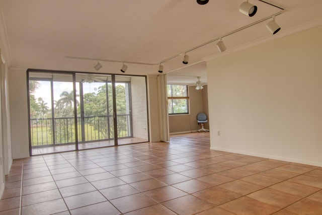 tiled spare room with crown molding and track lighting