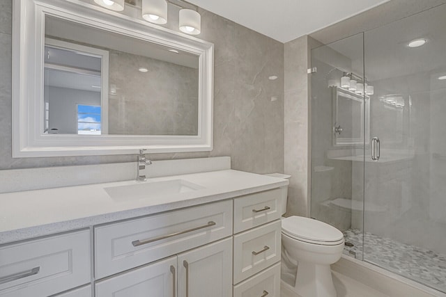 bathroom with toilet, vanity, and a shower with shower door