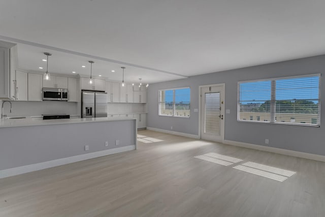 unfurnished living room with a chandelier, sink, and light hardwood / wood-style flooring