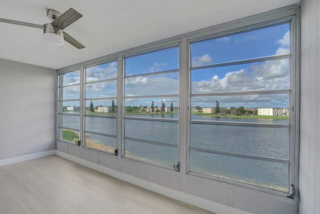 unfurnished sunroom with a water view and ceiling fan