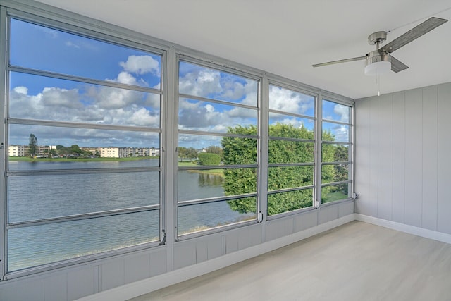 unfurnished sunroom featuring a water view and ceiling fan