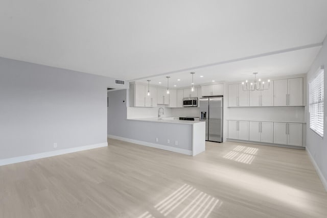 unfurnished living room with a chandelier, sink, and light hardwood / wood-style flooring